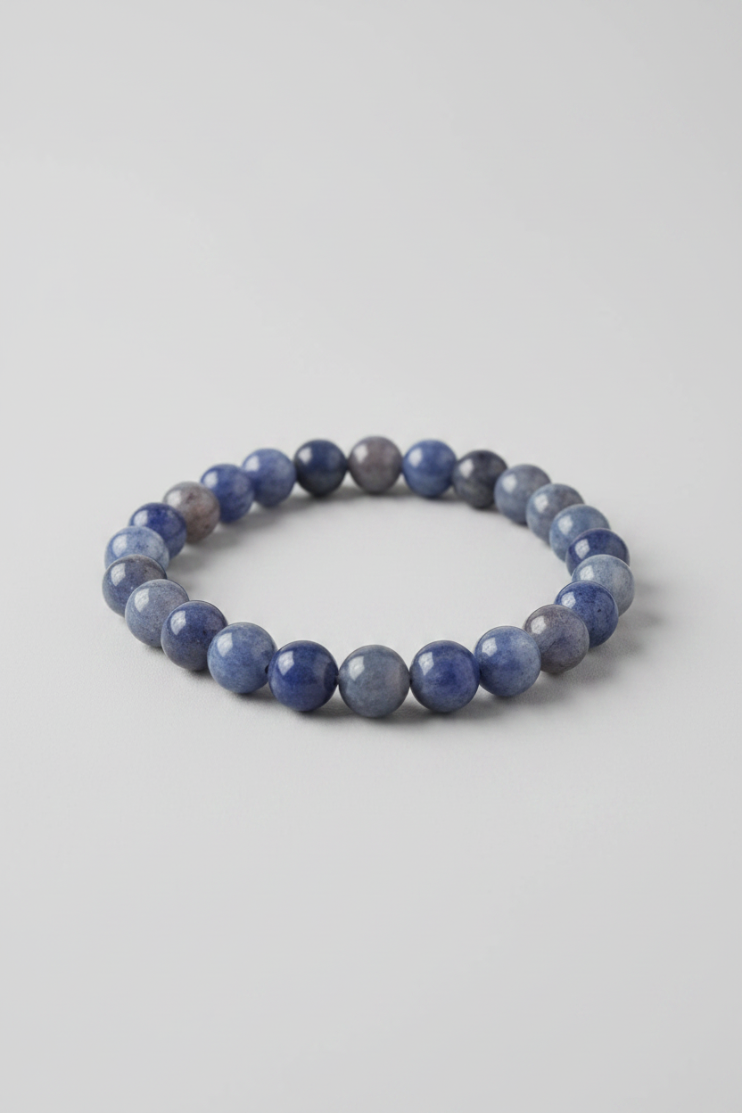 A Blue Aventurine Stone Bracelet displayed on a wooden surface with a beach background, and the EarthySoul Elements logo above it.