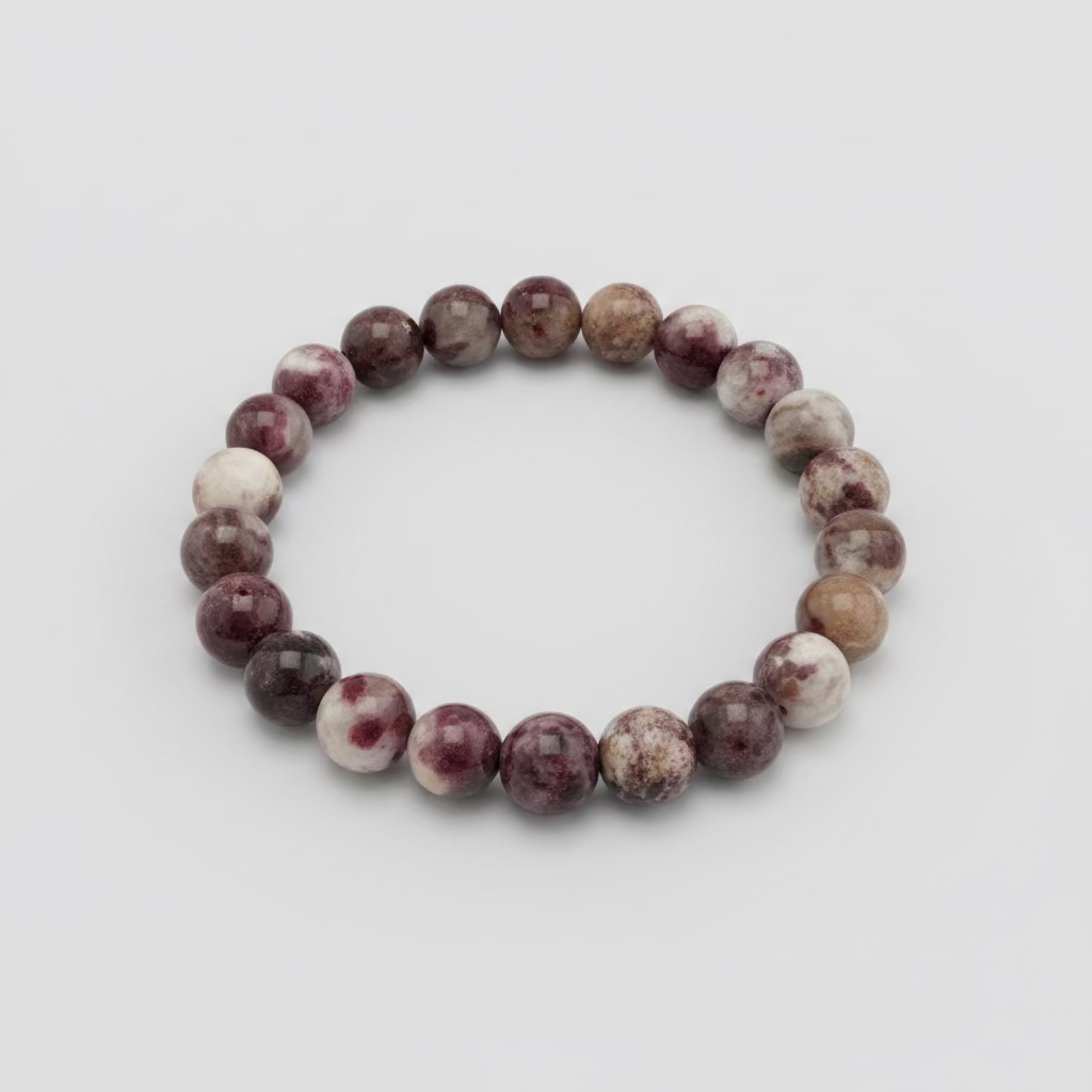 A beaded stretch bracelet made of round stone beads in shades of burgundy, purple, brown, and cream, resting on a wooden table outdoors.